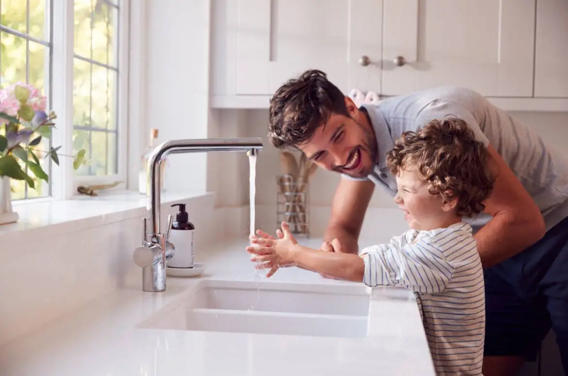 Come risparmiare su bolletta acqua - Immagine di giovane padre e figlio piccolo mentre si lava le mani