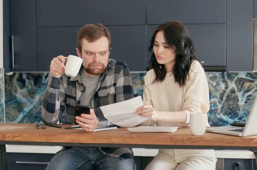 Come gestire le spese di casa - Coppia marito e moglie che controlla i conti di casa in salotto.