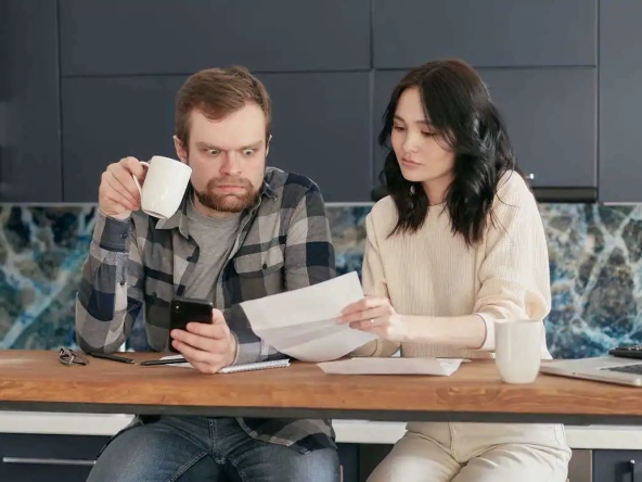 Come gestire le spese di casa - Coppia marito e moglie che controlla i conti di casa in salotto.